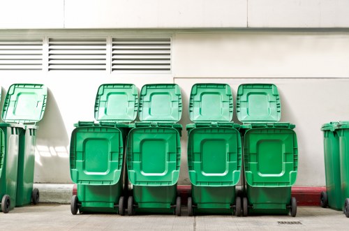 Operatives loading a skip with protective clothing visible